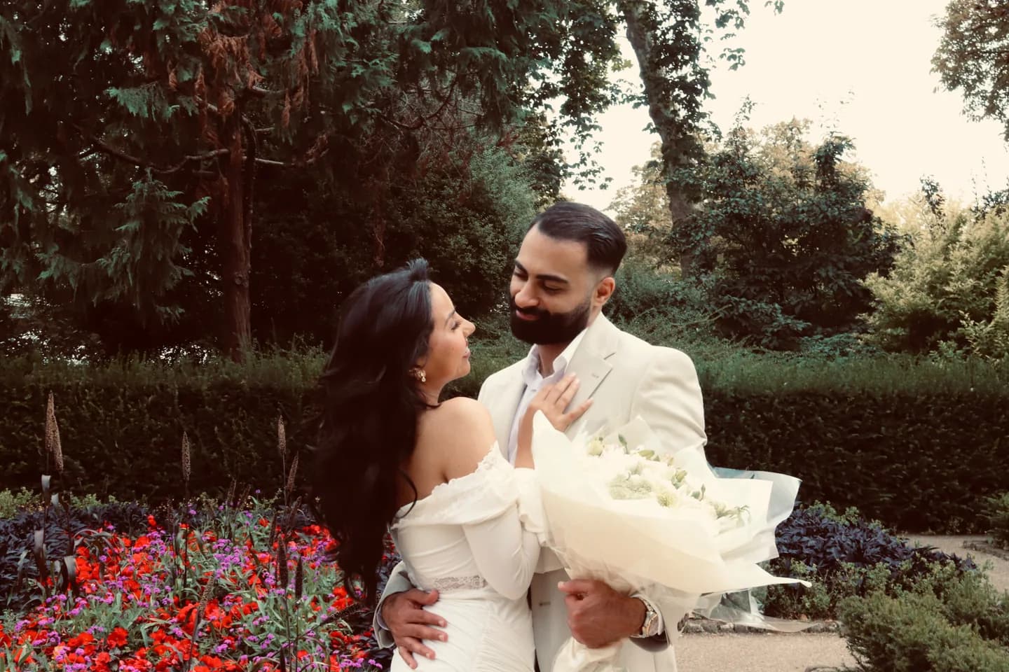 Fouad and Marina holding a bouquet together in a garden